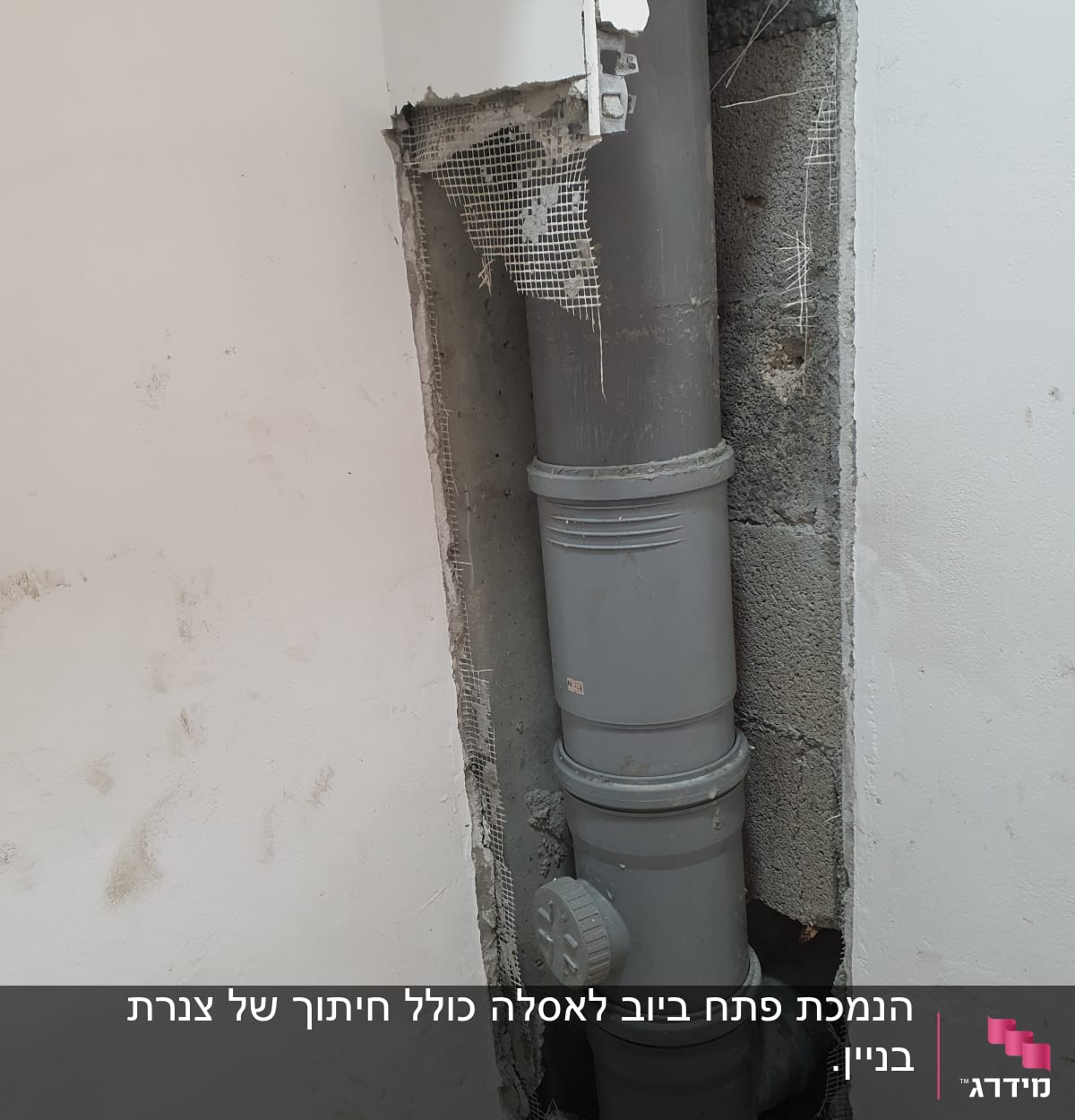 צינור ביוב אפור בקיר שבור עם רשת חשופה